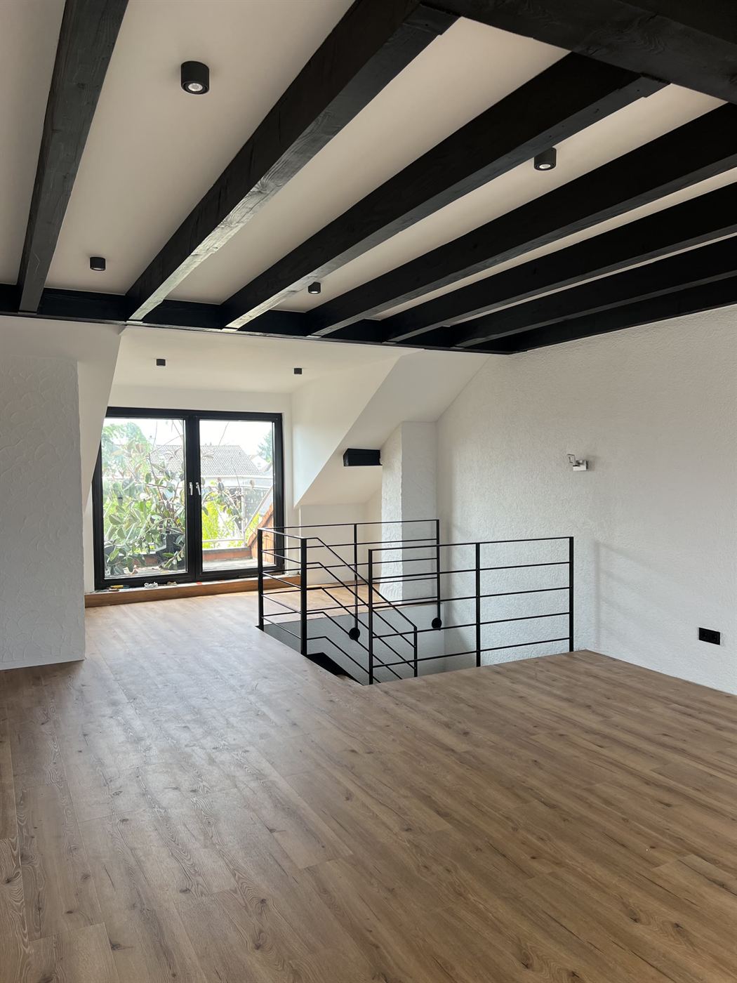 Galerie mit schwarzem Geländer über der Wohnebene des Lofts