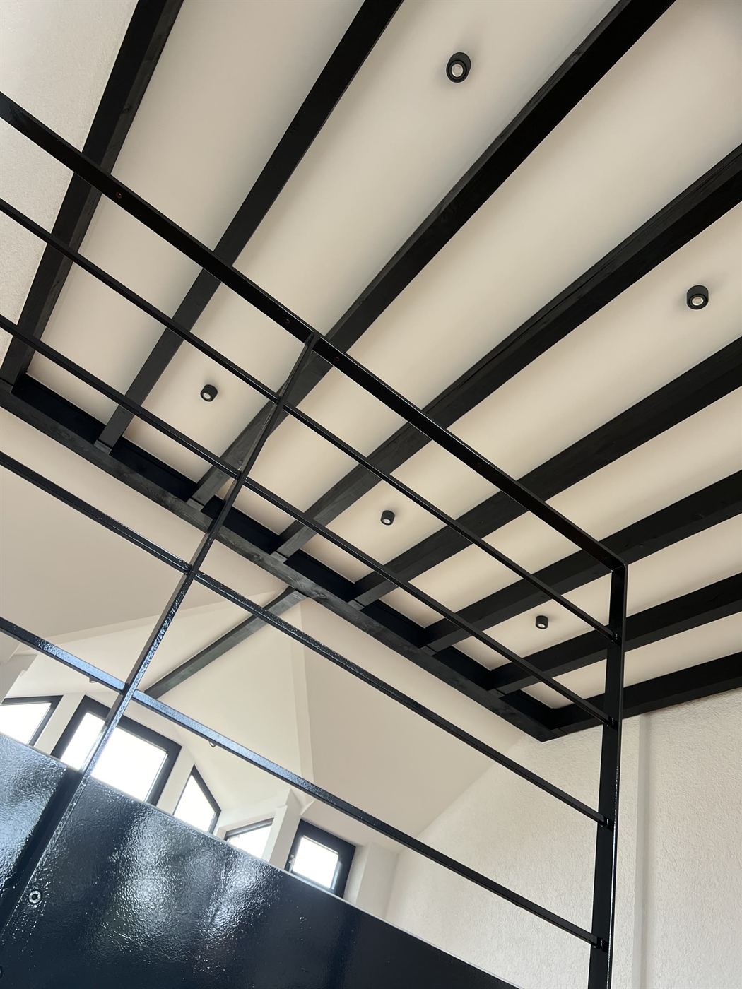Schwarz lackierte Holzbalken vor weißer Decke im Loft