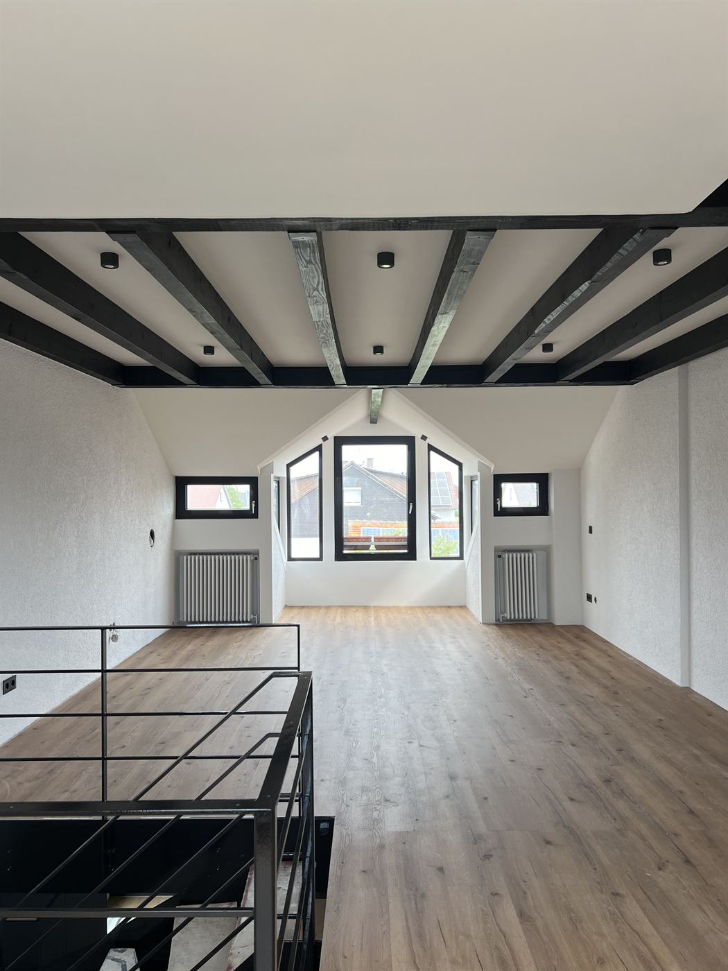 Loft mit schwarz lackierten Holzbalken